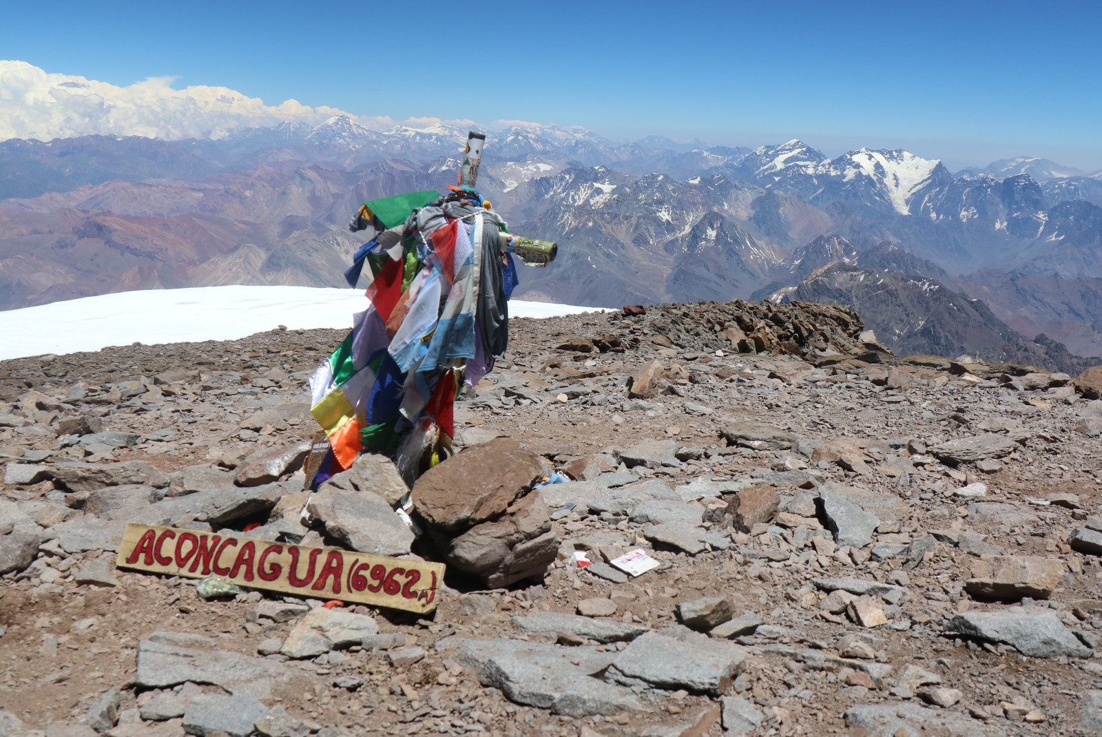 At the top of Aconcagua mountain in Mendoza Argentina overlooking a white snowcapped mountain range.