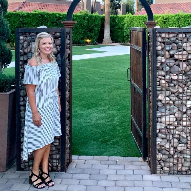 Travel advisor Anna Rush standing next to an open door in a fence while wearing a striped dress.