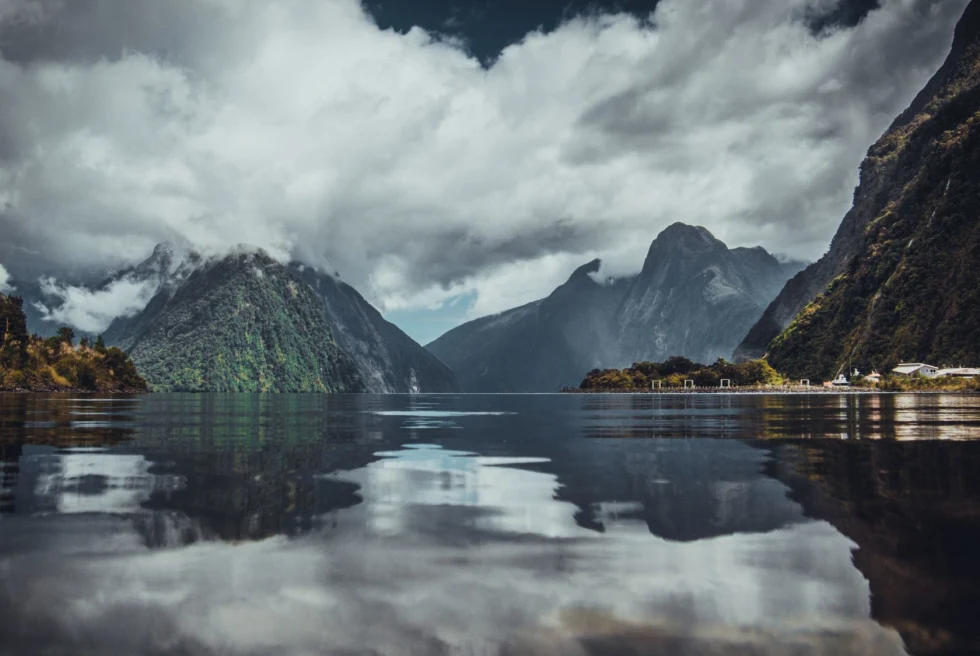 pristine mirrored lake with mountains shrouded by clouds