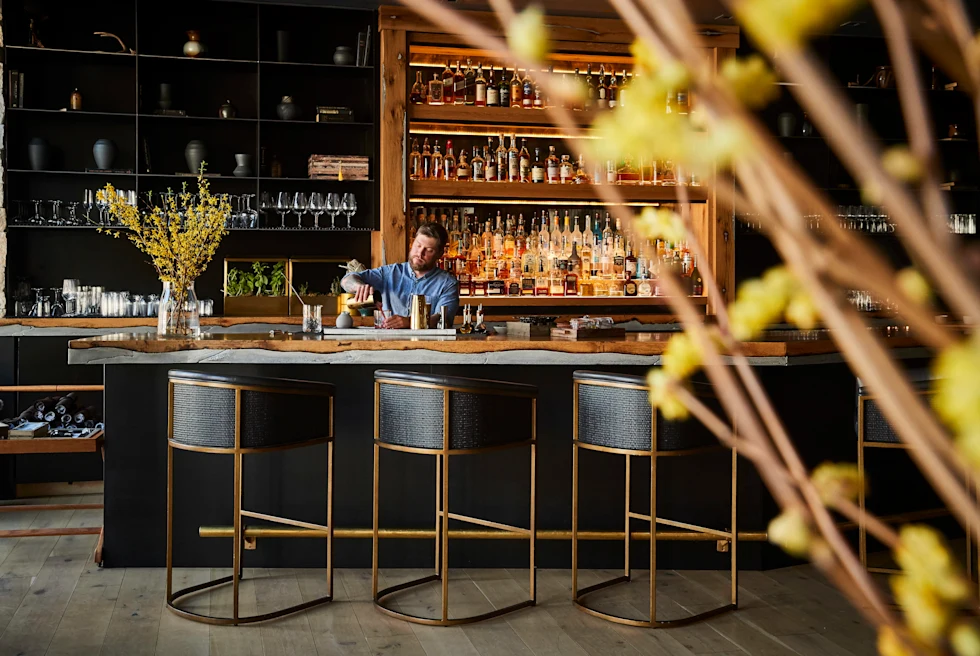 man standing behind bar with black chairs