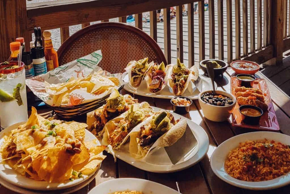 a full table of tacos and rice dishes on a beachfront porch