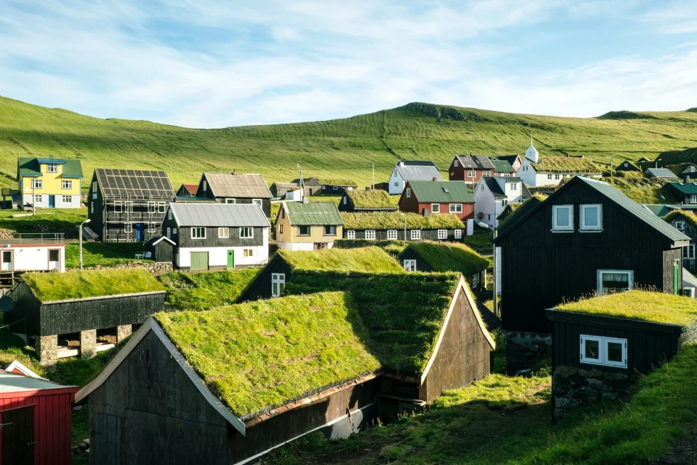 small moss grass and moss houses nestled in green hills with a blue sky