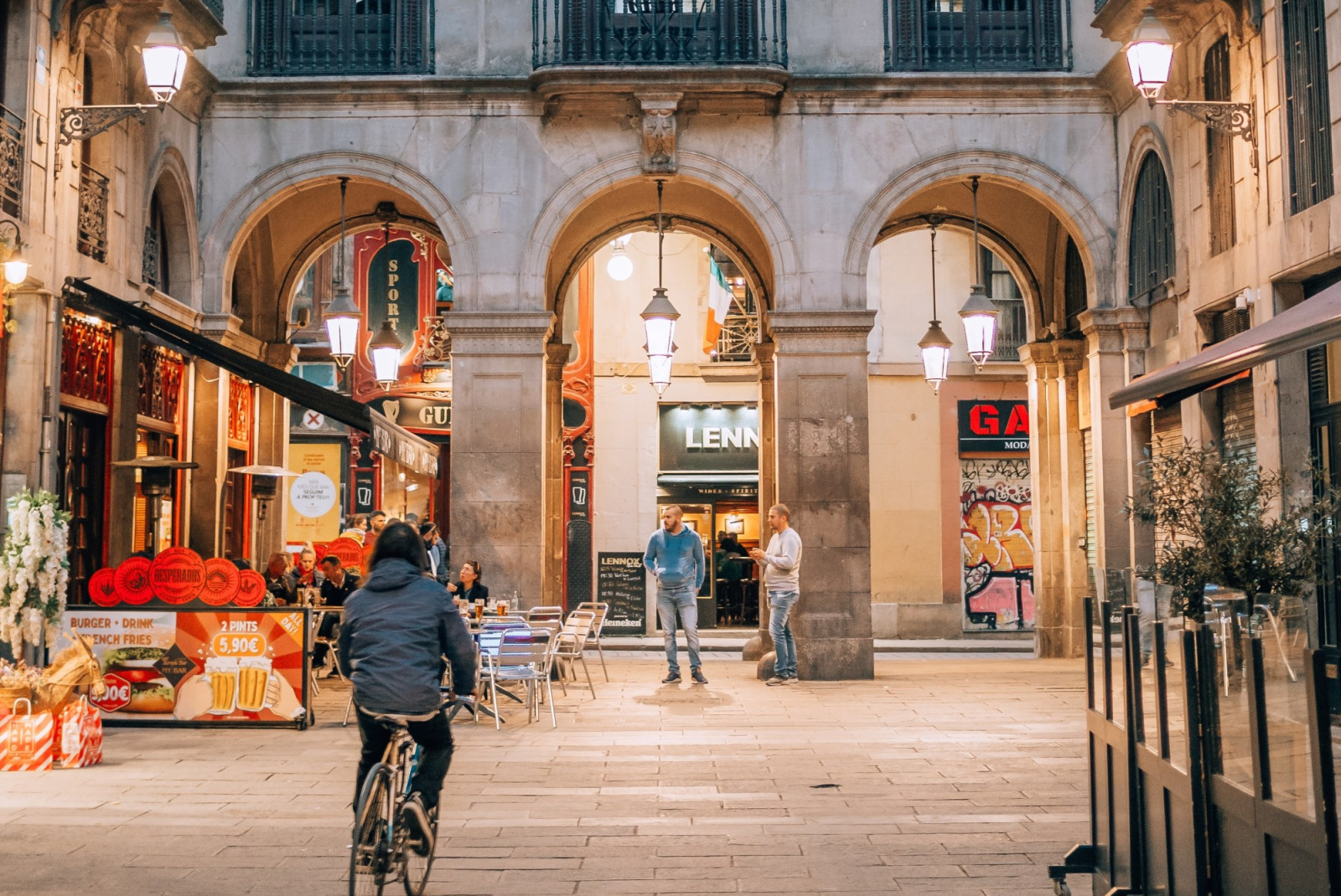 Biker and tourists hanging out in front of corner cafe in Barcelona's Gothic Quarter.