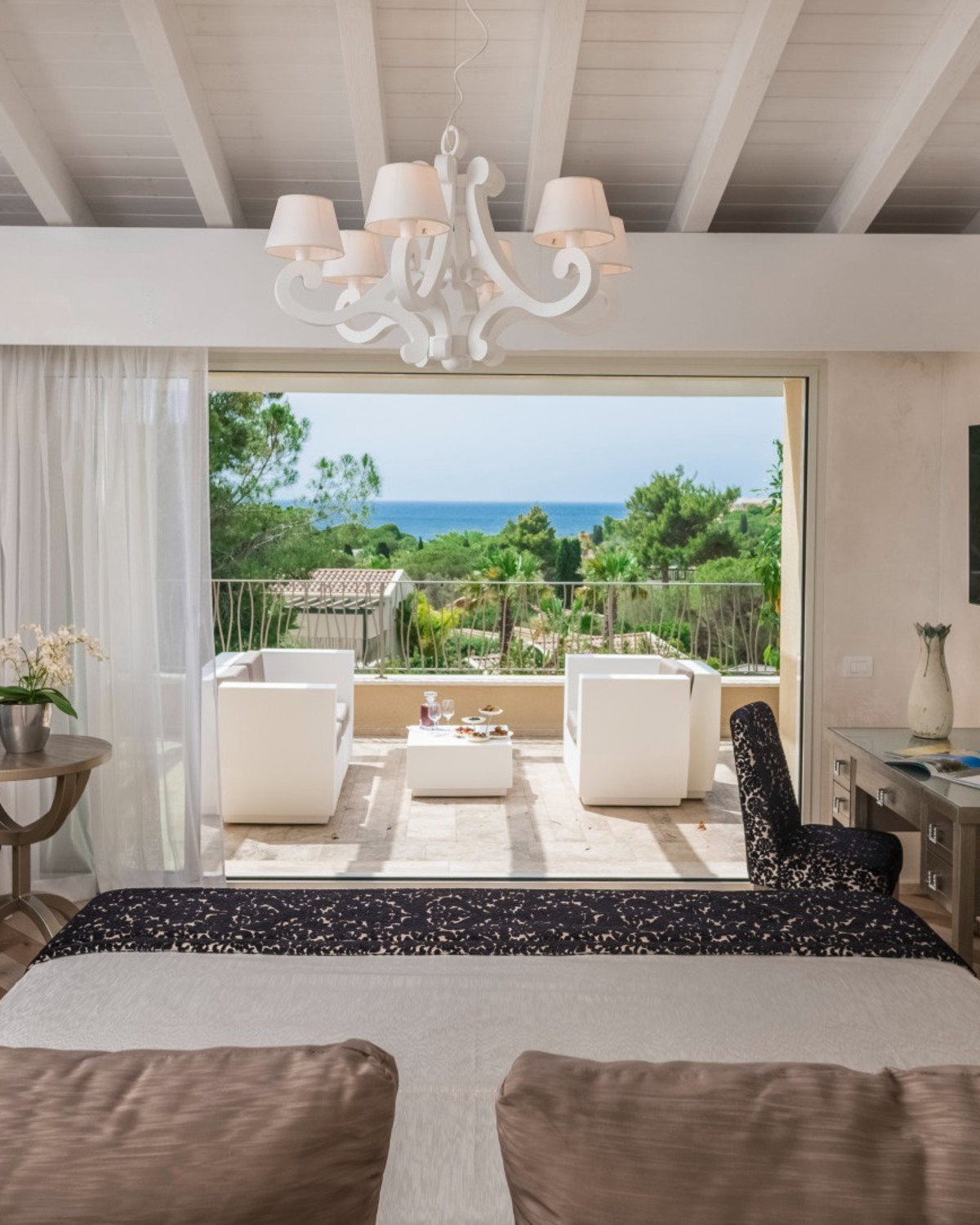 a living room with a white wooden chandelier overlooks the sea