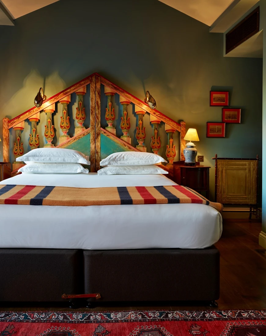 a plush bed in a fancy hotel room with teal walls and a dark-wood floor