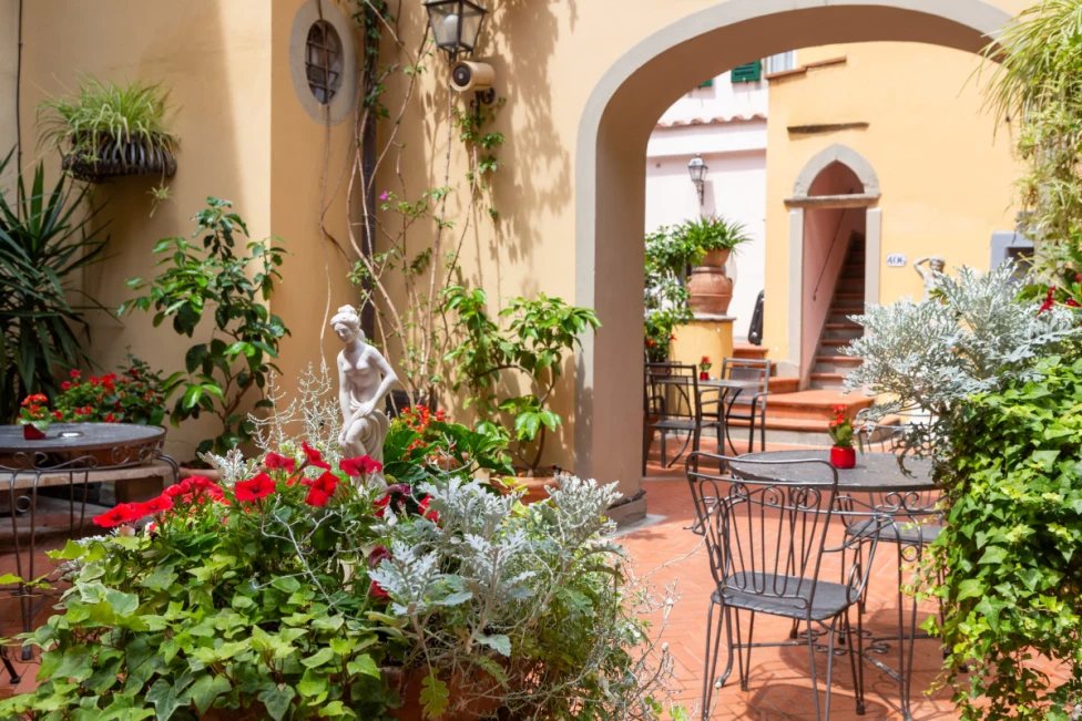 The garden at the Rivoli Boutique Hotel, with plants and sculptures in a yellow-painted courtyard.
