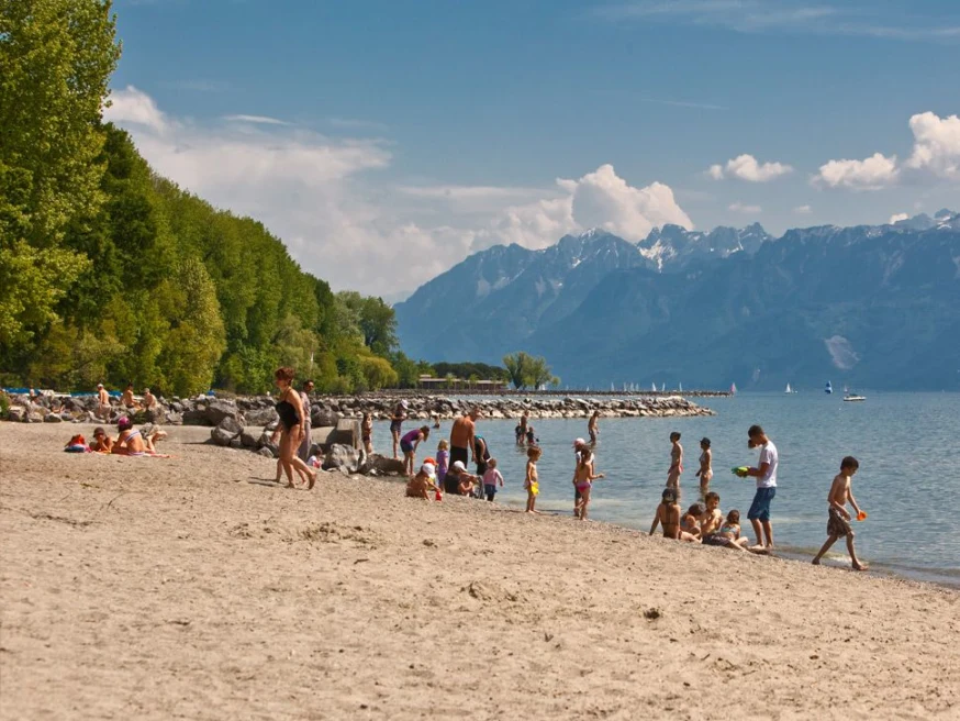 people standing on a beach with mountains in the background