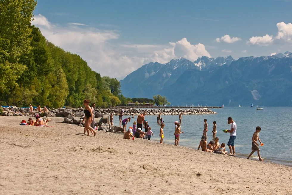 people standing on a beach with mountains in the background