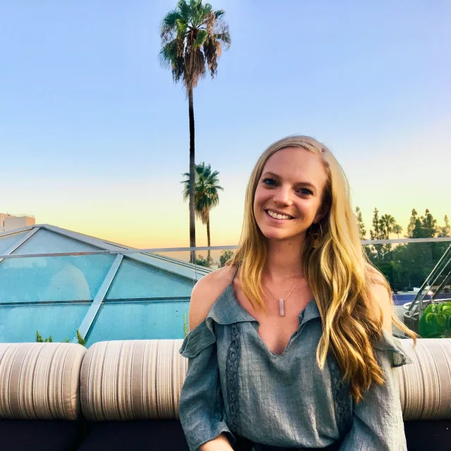 Travel Advisor Lauren Hackney with a gray shirt and palm trees in the background.