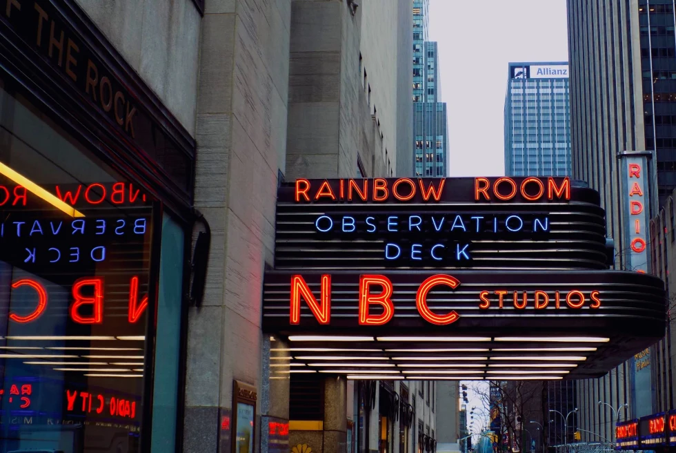 Red signs on the side of building read, Rainbow Room, NBC studios