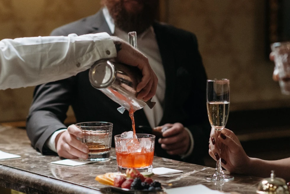 A bar tender putting cocktail in a glass. 