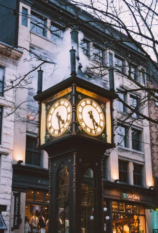 A picture of a brown wooden analog clock on the streets.