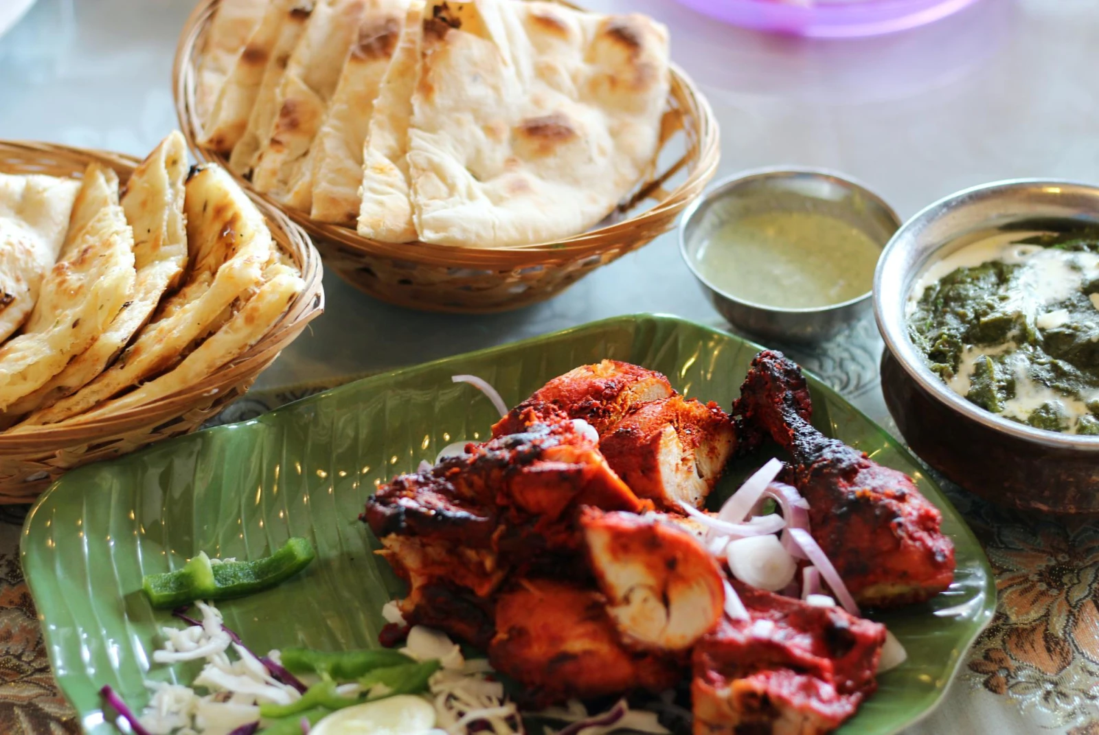 Tandoori chicken and naan with sauces on restaurant table.