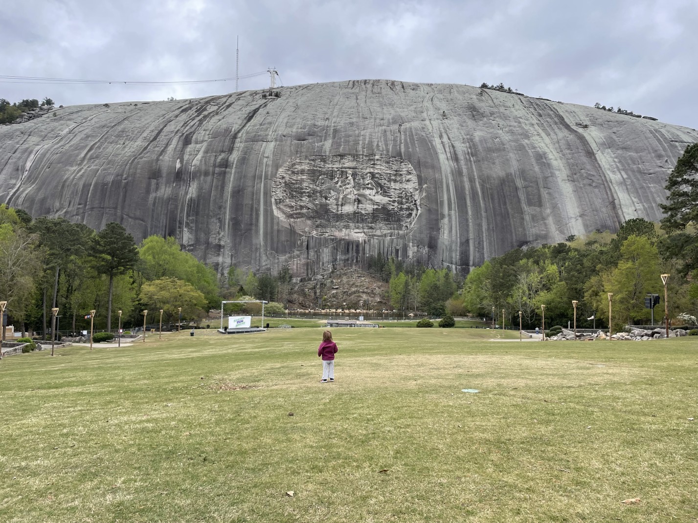 Grey Stone Mountain in Atlanta, Georgia with a child in red standing on green grass.
