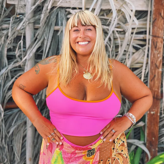 Travel Advisor Heather Brown in a pink shirt in front of branches and wooden pole.