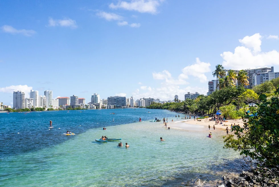 tropical white sand beach with a modern city in the distance