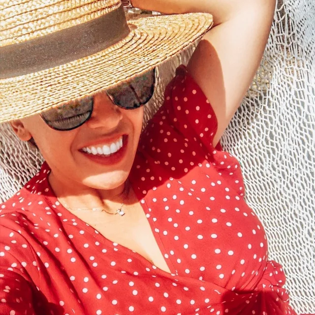 Charlotte wearing a polka dot print red dress, straw hat and sunglasses