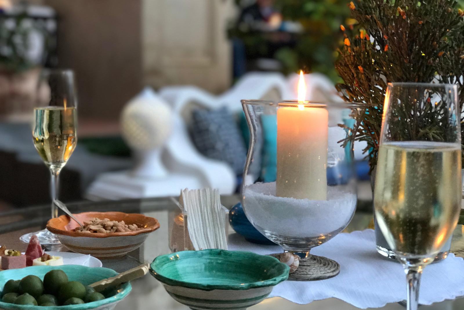 Two glasses of wine, candle and bowl of olives on table in Positano