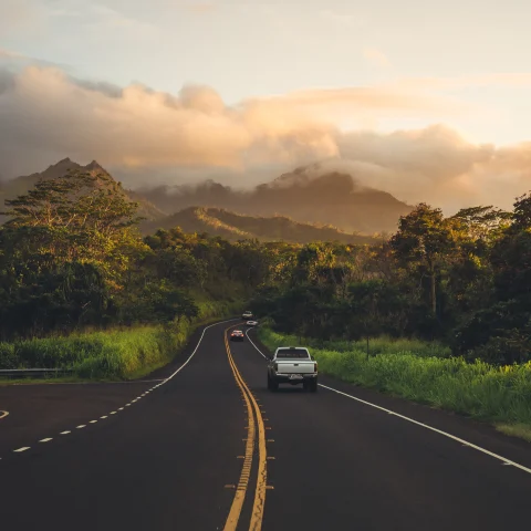 A highway in Hawaii framed by mountains and clouds. 