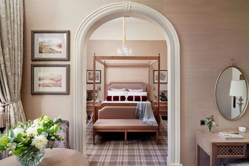 a hotel bedroom with a white arch and plaid carpeting