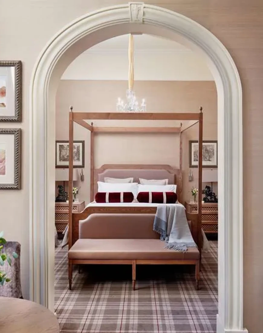 a hotel bedroom with a white arch and plaid carpeting