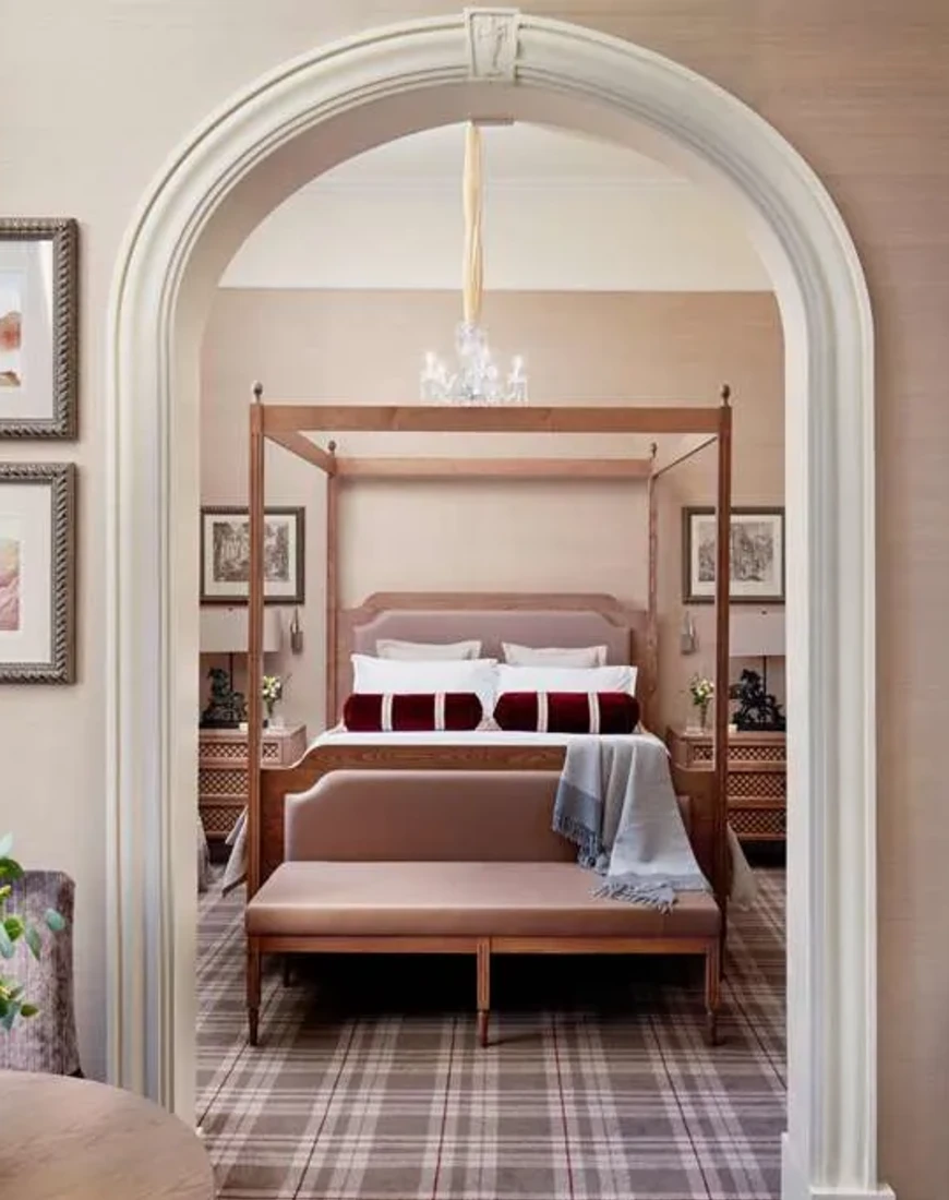 a hotel bedroom with a white arch and plaid carpeting