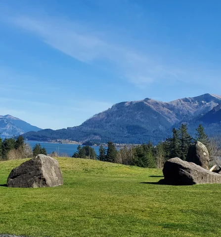 A photo of boulders, a lake and the Columbia River Gorge in the background. 