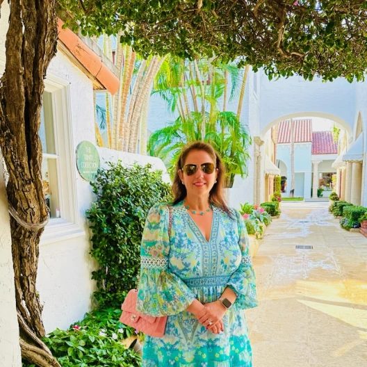 Travel Advisor Lindsay Burkhead in a blue floral dress in front of a tree.