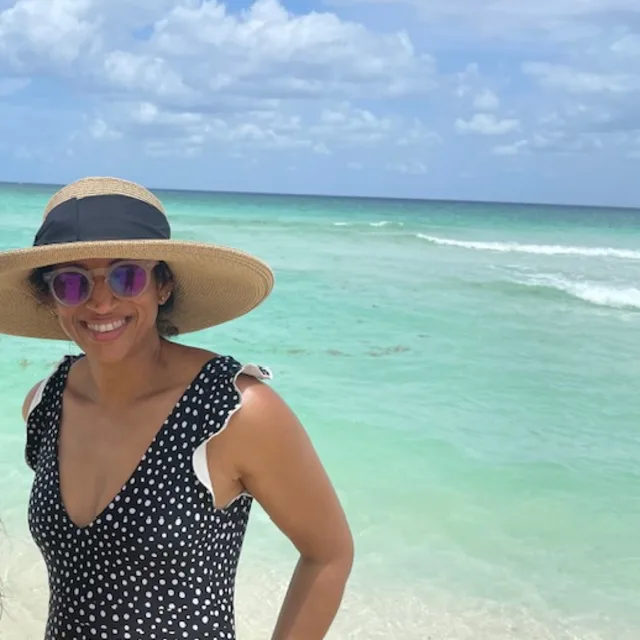 FORA travel agent Kirti Rao wearing wide brimmed hat and black bathing suit on the beach