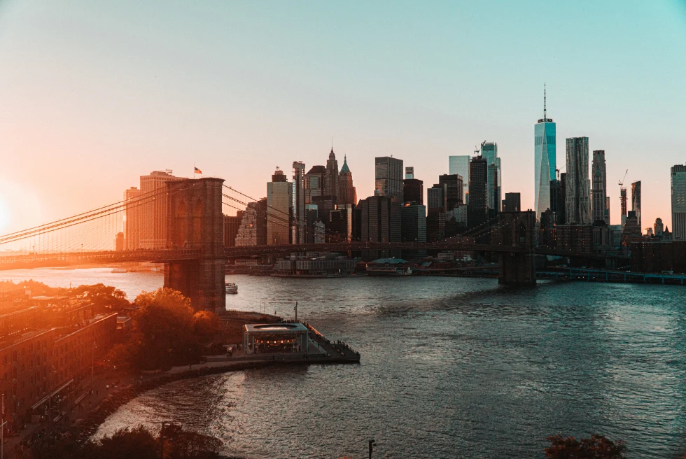 Brooklyn Bridge with NYC skyline at sunset.