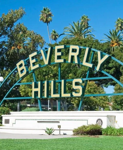 Beverly Hills signage at Beverly Gardens Park with palm trees and a clear sky in the distance.