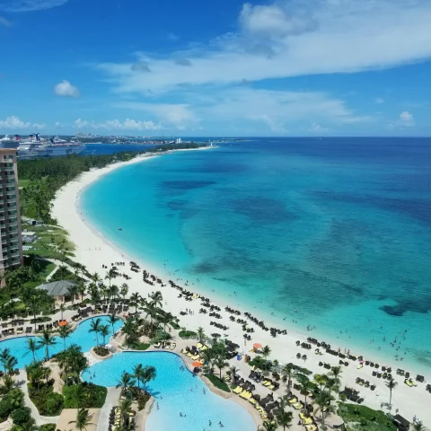 aerial view of blue ocean and white sand next to tall buildings