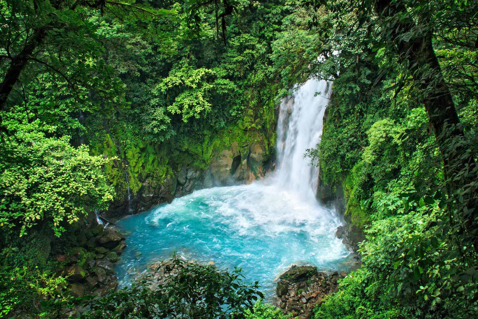 Lush blue waterfall surrounded by jungle in Costa Rica. 