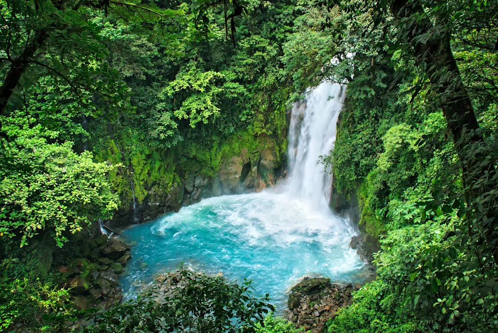 Lush blue waterfall surrounded by jungle in Costa Rica.