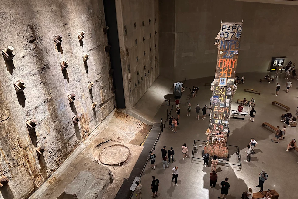 Inside of a museum with big brown walls, benches and people.