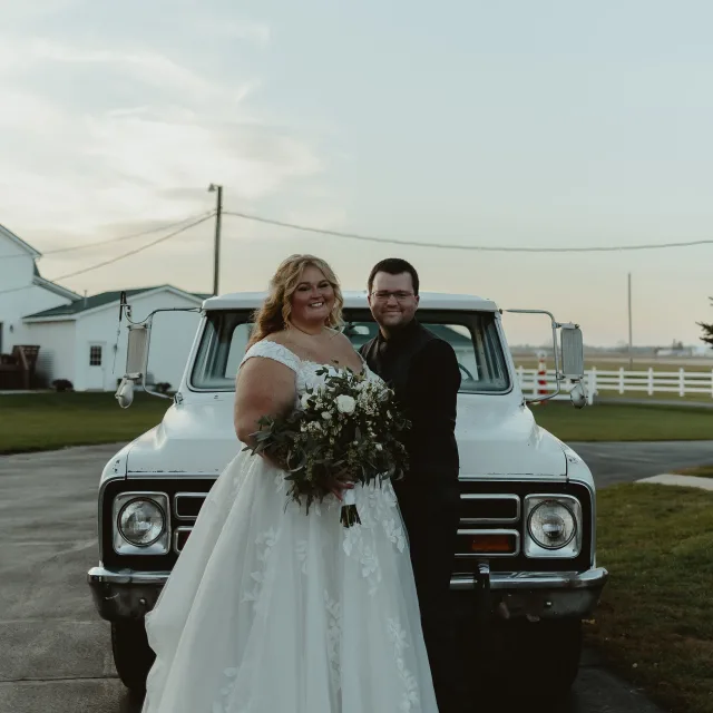 Travel Advisor Dane Doremus in a tux with partner in wedding dress in front of a white truck.