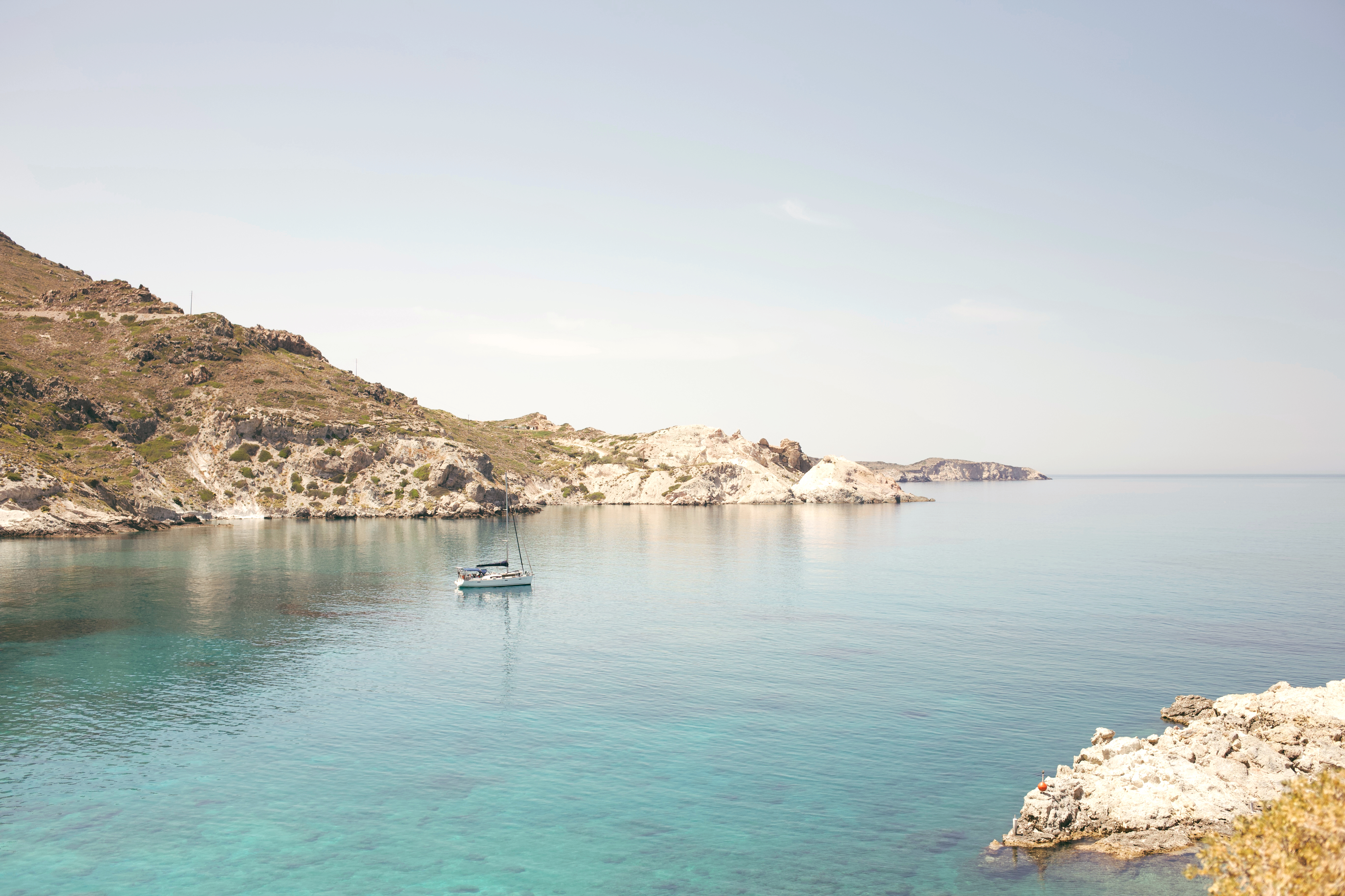 Boat in body of water next to cliffs during daytime