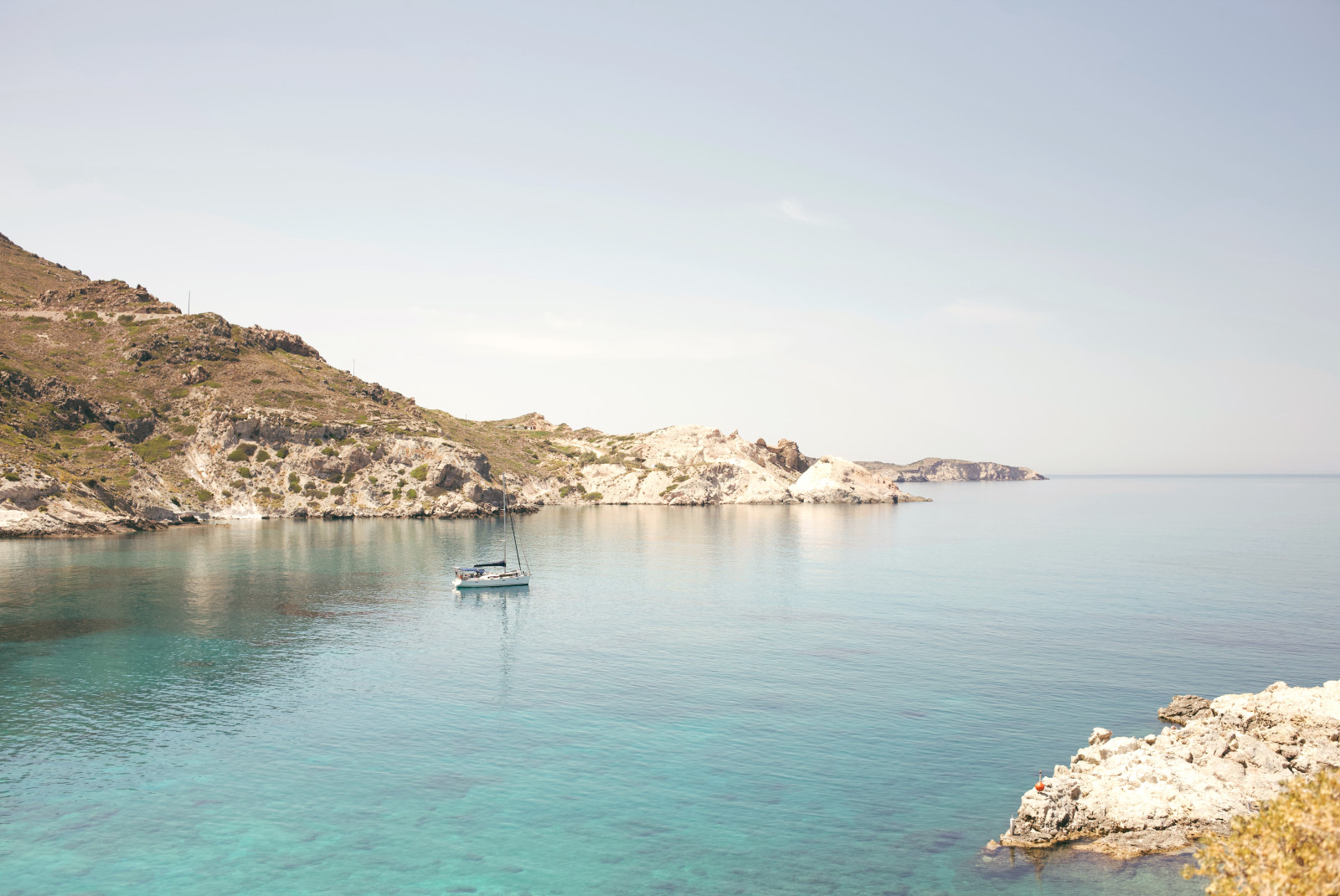 Boat in body of water next to cliffs during daytime