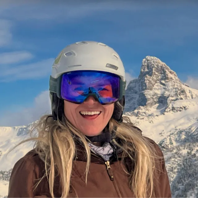 Travel advisor wearing Ski goggles, standing on a snowy mountain.