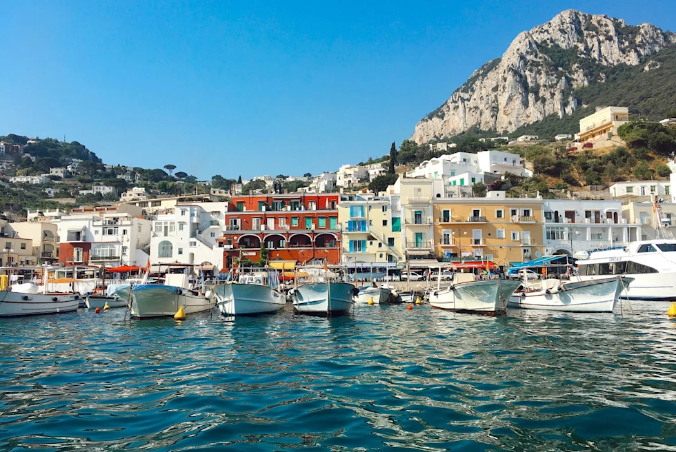 boats in an island's harbor with colorful buildings along the water