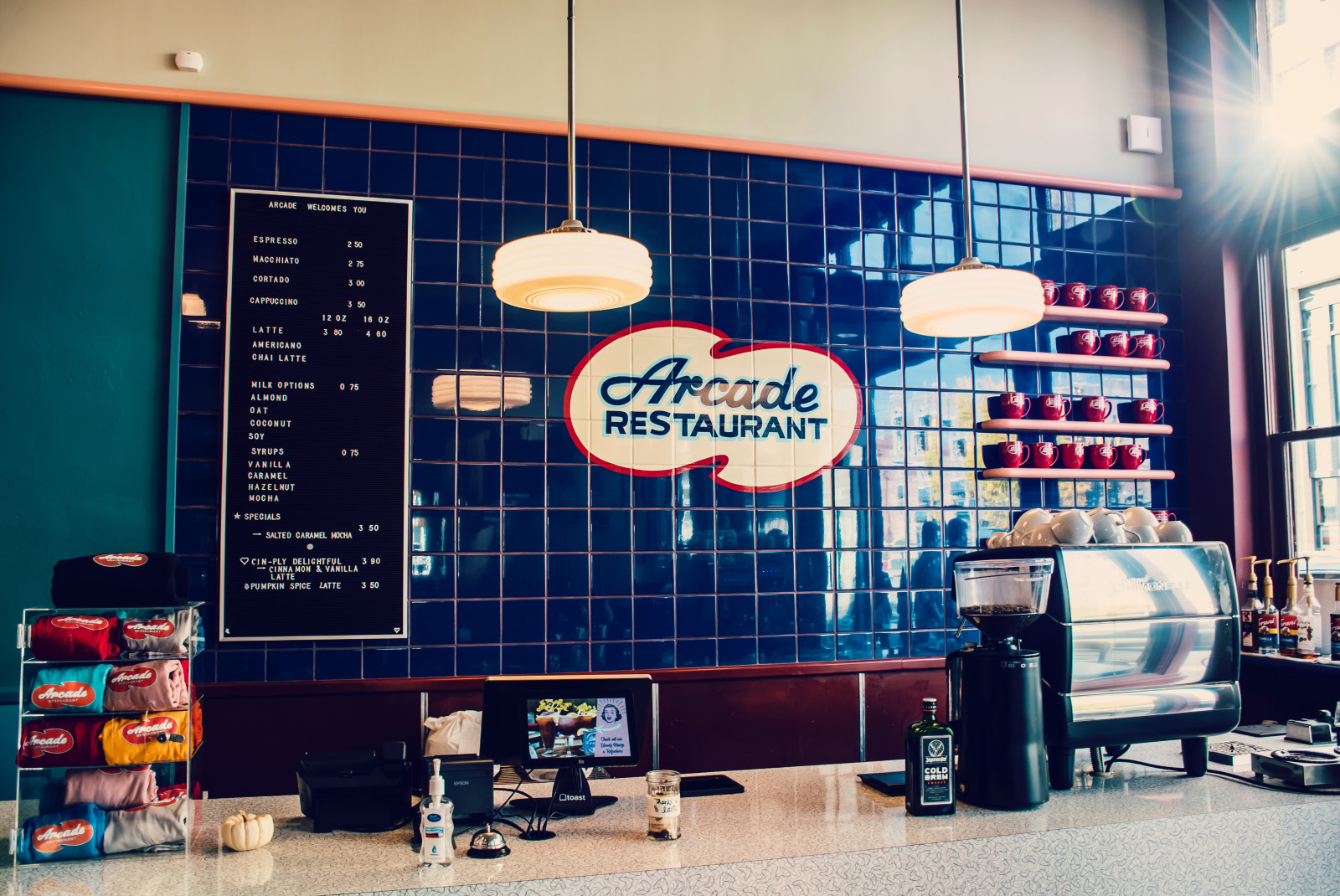 White restaurant counter with hanging lights and blue tiling on the wall 