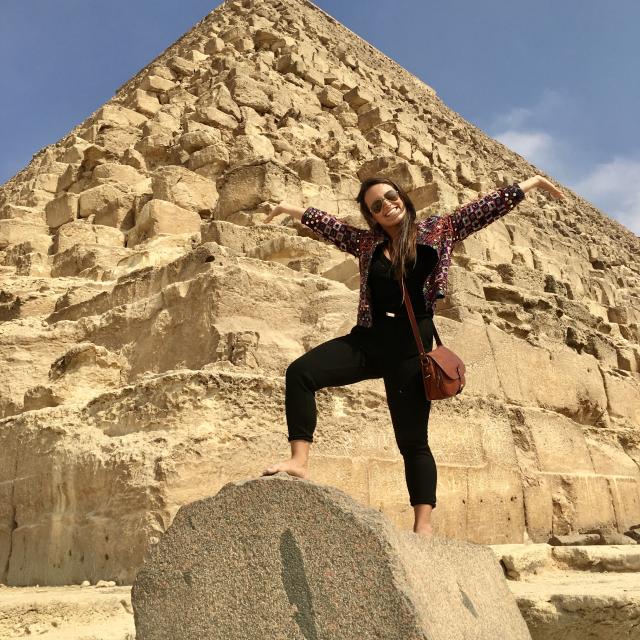 Woman wearing black shirt and pants standing on rock with blue skies