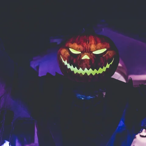 A carved pumpkin with lights inside seeming like a ghost. 