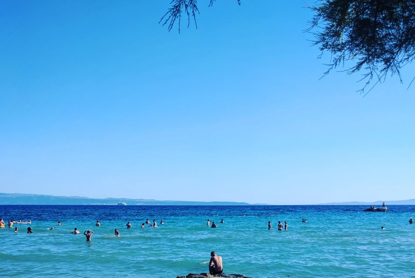 people wade in clear blue waters and sky 