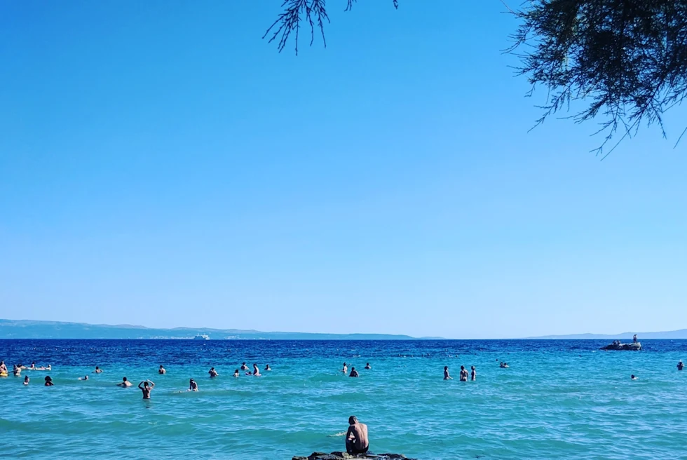 people wade in clear blue waters and sky