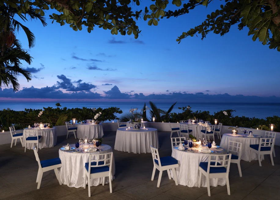 white tables and chairs outside next to body of water during sunset