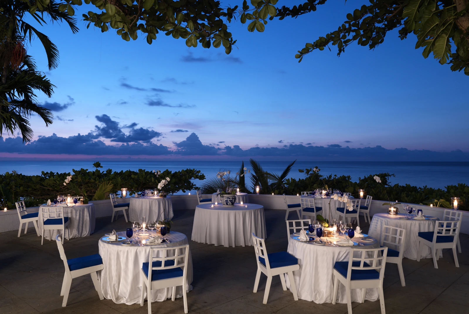 white tables and chairs outside next to body of water during sunset