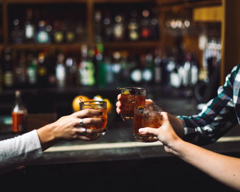 friends cheers cocktails at dark wood bar