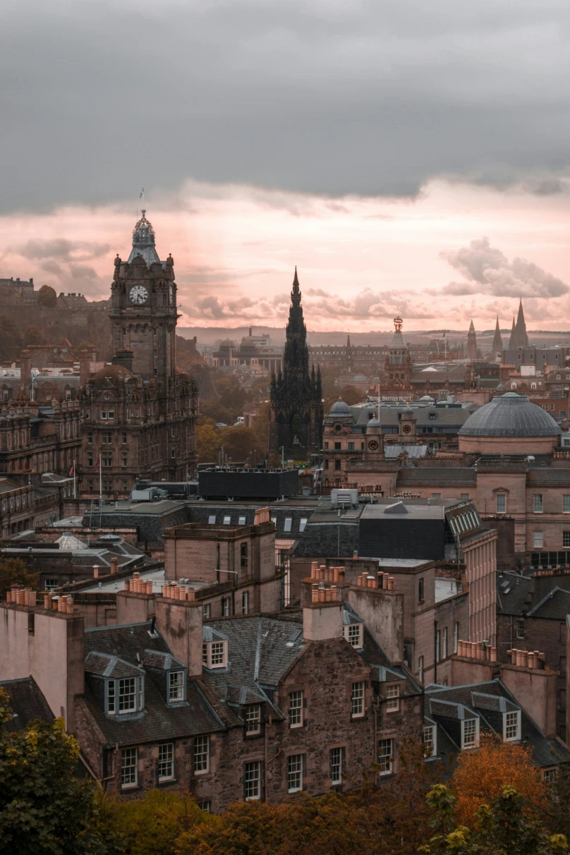 Aerial view of the city of Edinburgh with clock tower and old buildings including the best restaurants in Edinburg in dim evening light