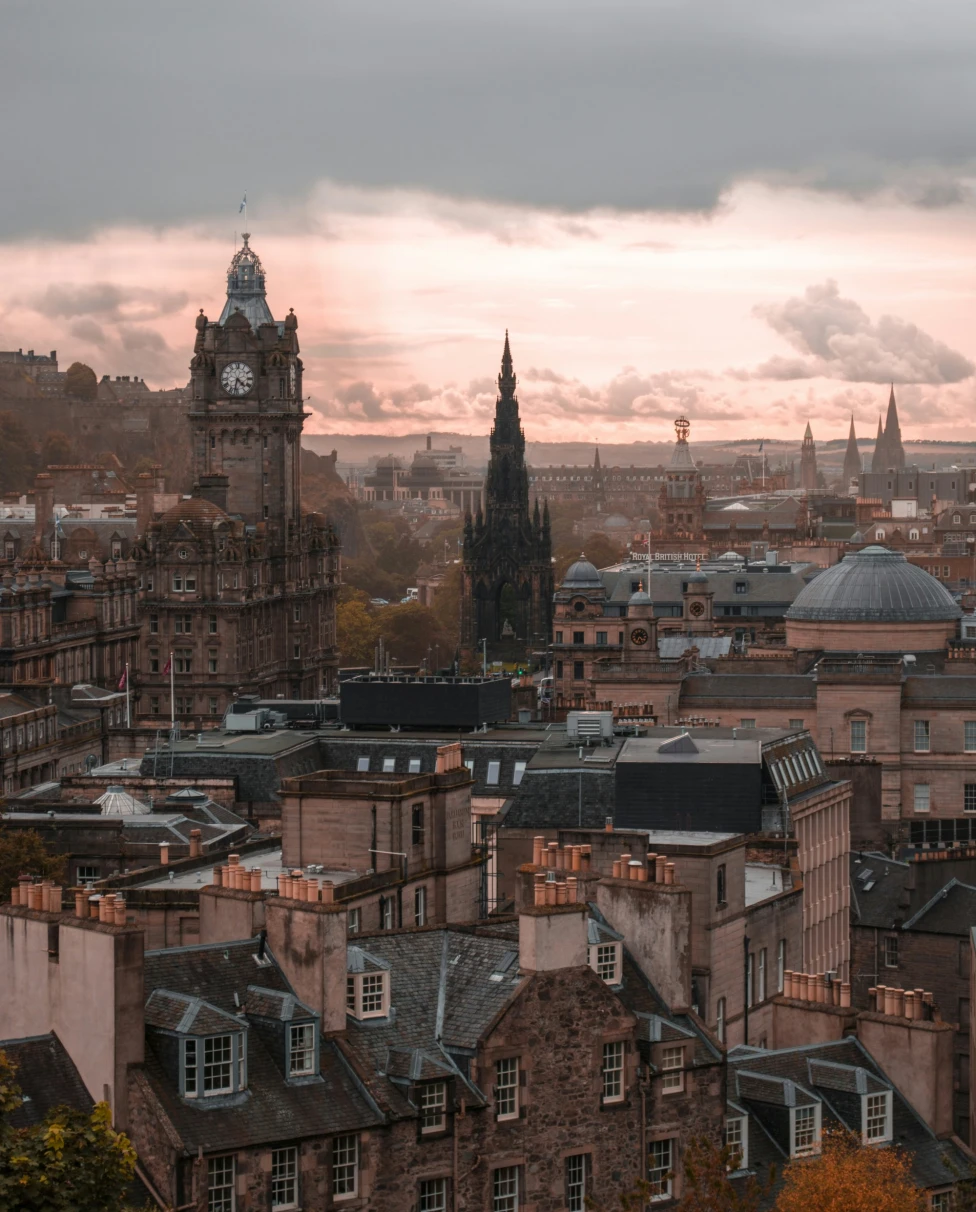 Aerial view of the city of Edinburgh with clock tower and old buildings including the best restaurants in Edinburg in dim evening light